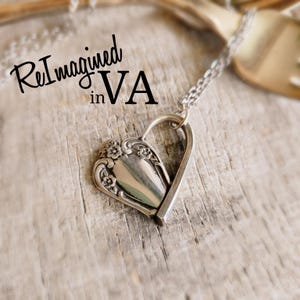 May include: A silver-toned heart-shaped pendant crafted from a repurposed spoon handle, featuring embossed floral details and a delicate chain. The text ReImagined in VA is visible in the upper left corner of the image.