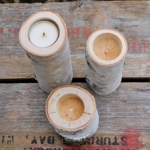 May include: Three birch bark candle holders with a natural wood finish. Each holder has a round opening for a tea light candle.