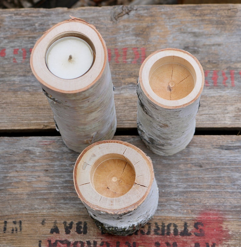 May include: Three birch bark candle holders with a natural wood finish. Each holder has a round opening for a tea light candle.