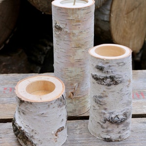 May include: Three white birch bark candle holders of varying sizes. The candle holders are made from natural birch wood and have a smooth, polished finish.