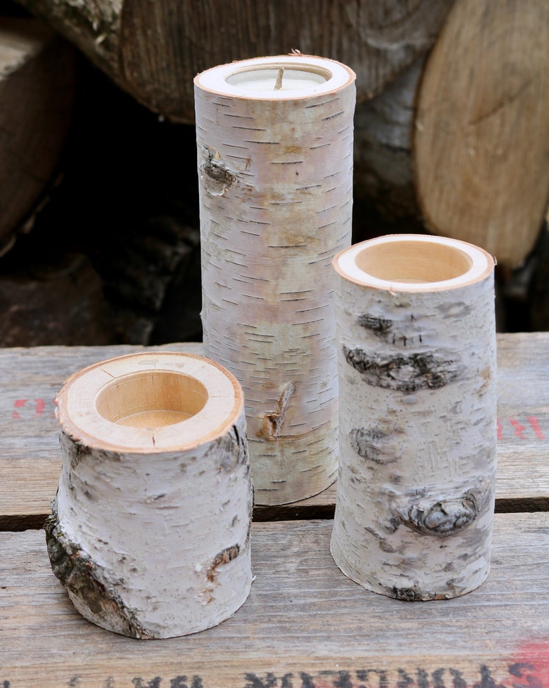 May include: Three white birch bark candle holders of varying sizes. The candle holders are made from natural birch wood and have a smooth, polished finish.