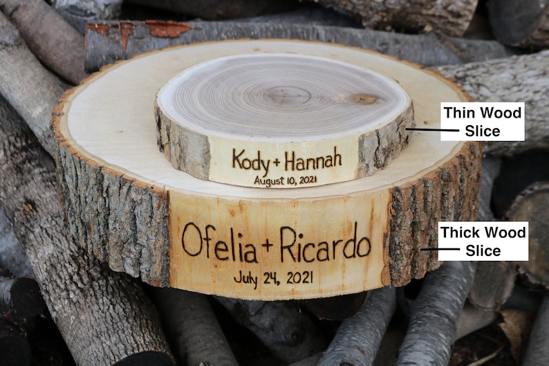 K&ouml;nnte beinhalten: Zwei Holzscheiben, eine auf der anderen. Die obere Scheibe ist d&uuml;nner und hat den Text "Kody + Hannah August 10, 2021" eingraviert. Die untere Scheibe ist dicker und hat den Text "Ofelia + Ricardo July 24, 2021" eingraviert.