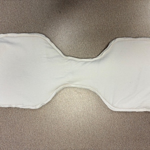 May include: A white, hourglass-shaped cloth diaper insert. The insert is made of a soft, absorbent material and has a stitched edge. The insert is designed to be placed inside a cloth diaper for added absorbency.