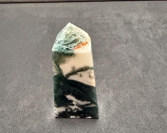 May include: A green, white, and orange agate crystal point. The crystal is polished and has a smooth surface.