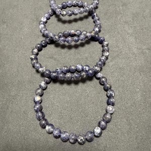 May include: Four stacked bracelets made of dark blue and silver beads.