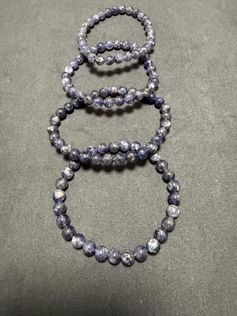 May include: Four stacked bracelets made of dark blue and silver beads.