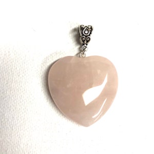 May include: A pale pink heart-shaped pendant made of rose quartz with a silver bail.