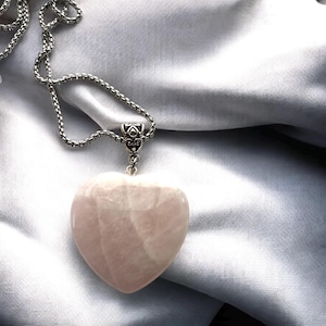 May include: A silver chain necklace with a heart-shaped rose quartz pendant.