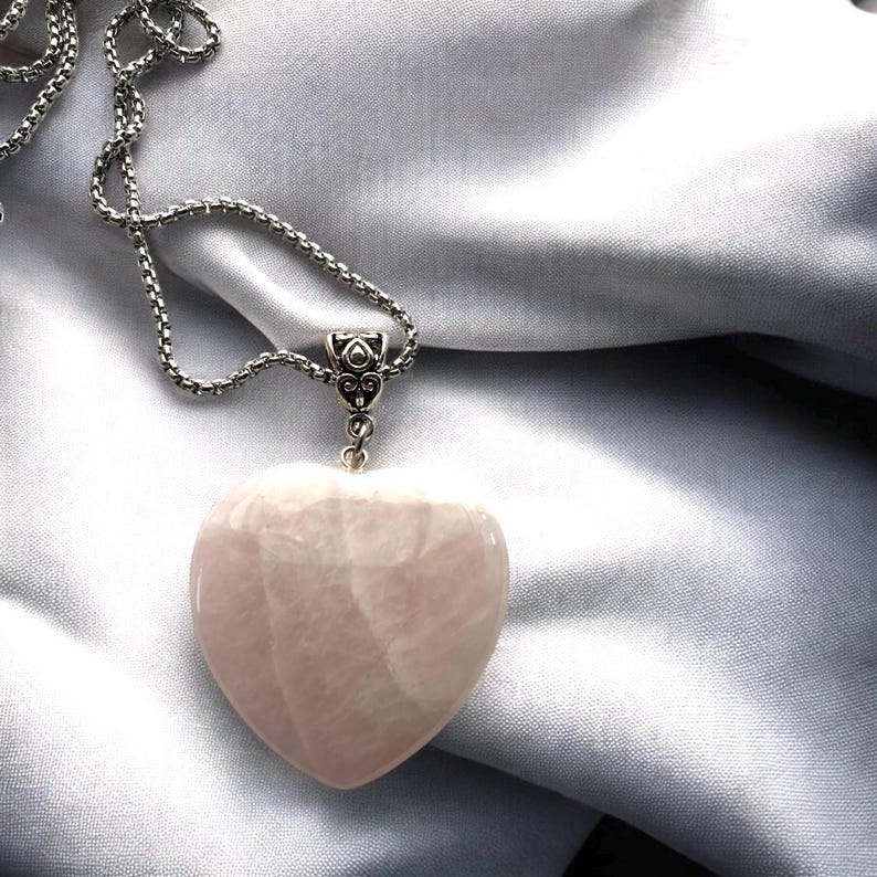 May include: A silver chain necklace with a heart-shaped rose quartz pendant.