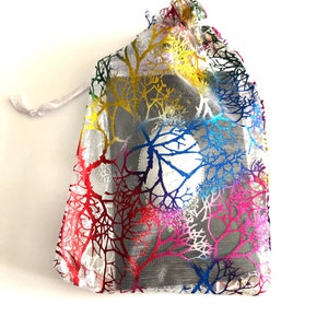 May include: A small, white, mesh drawstring bag with a colorful tree pattern. The bag is made of a sheer material and has a drawstring closure.