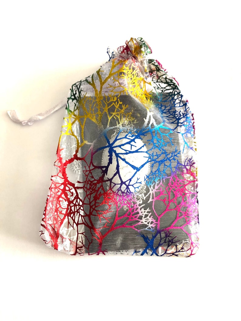 May include: A small, white, mesh drawstring bag with a colorful tree pattern. The bag is made of a sheer material and has a drawstring closure.
