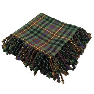 May include: A green, brown, and black plaid scarf with a fringed edge. The scarf features a classic tartan pattern with yellow and blue accent lines. The fringe is a mix of green, brown, and gold twisted threads.