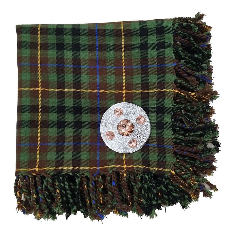 May include: A green, brown, and black plaid scarf with a silver brooch. The scarf has a fringed edge and a pattern of yellow and blue lines. The brooch is round with a central gem and three smaller gems.