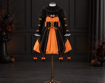 May include: A black and orange dress featuring a ruffled collar, long sleeves with small bows, and a corset-style bodice with crisscross lacing. The skirt has a layered design with black panels over an orange base, accented by small orange bows.