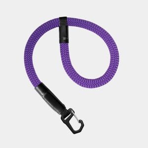 May include: A purple braided rope lanyard featuring a black plastic connector and a black metal carabiner clip. The rope is formed into a circular loop, secured by a black fabric sleeve at the top and a black plastic attachment point at the base.