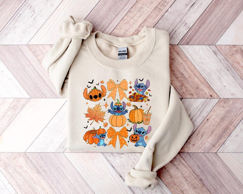 Puede incluir: Sudadera beige de cuello redondo con un gr&aacute;fico colorido con tem&aacute;tica de Halloween. El dise&ntilde;o incluye calabazas, hojas de oto&ntilde;o, lazos y un personaje de dibujos animados azul. La sudadera est&aacute; hecha de un material suave y es perfecta para el oto&ntilde;o.