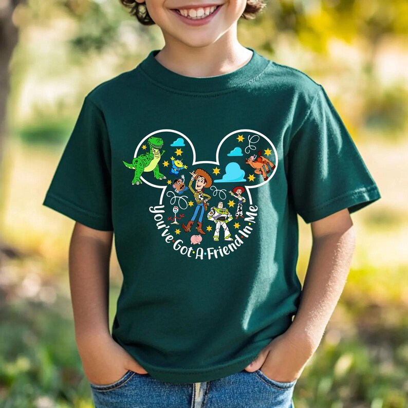 May include: Dark green t-shirt featuring a Mickey Mouse-shaped design with characters from the Toy Story movie. The design includes Woody, Buzz Lightyear, and other characters, with the text "You've Got A Friend In Me".