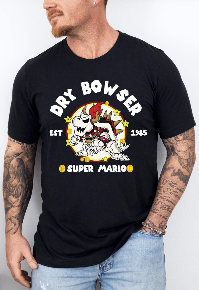 May include: Black t-shirt featuring a graphic of Dry Bowser from Super Mario. The design includes the text "DRY BOWSER" above the character, with "EST 1985" and "SUPER MARIO" below. The character is in red, white, and yellow.