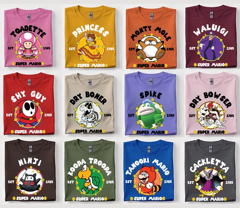 May include: A collection of Super Mario themed t-shirts in various colors, each featuring a different character graphic and the text "EST 1985 SUPER MARIO". Characters include Toadette, Princess, Monty Mole, Waluigi, Shy Guy, Dry Boner, Spike, Dry Bowser, Ninji, Koopa Troopa, Tanooki Mario, and Cackletta.