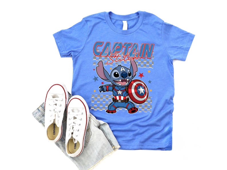 May include: A light blue t-shirt with the words "CAPTAIN Stitch" and a cartoon character holding a shield. White sneakers and denim shorts are placed below the shirt. The shirt features a graphic of Stitch as Captain America.