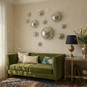 Op de afbeelding: Een woonkamer met een groene fluwelen bank, kussens en een bijzettafel met een lamp. De muur is versierd met spiegelende discoballen van verschillende groottes. De kamer heeft een warme en uitnodigende sfeer.