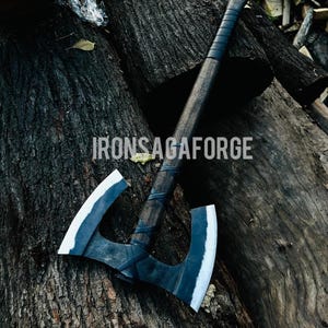 May include: A handcrafted double-bit axe with a dark wooden handle and two curved blades. The blades have a white edge and a dark gray body. The axe is resting on a pile of dark brown logs. The text "IRONSAGAFORGE" is visible.