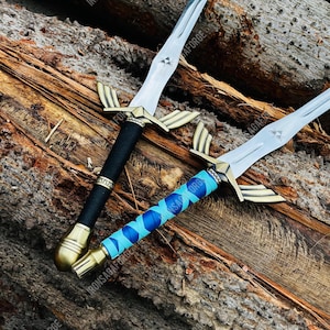 May include: Two decorative swords with silver blades and gold-colored crossguards. One sword has a black handle, and the other has a blue and light blue wrapped handle. The swords are displayed on a wooden surface. The text "IRONSAGAFORGE" is visible.