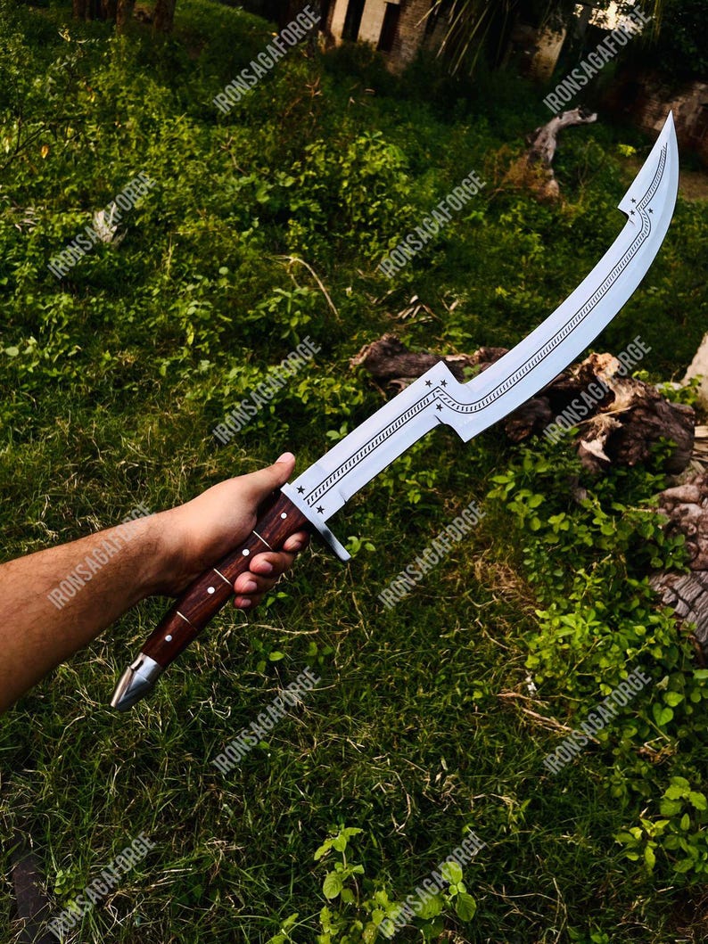 May include: A curved, silver-colored sword with a wooden handle is held against a backdrop of green foliage. The blade features decorative etchings and star-shaped accents. The handle is a dark brown color with silver accents. The text "IRONSAGAFORGE" is visible.