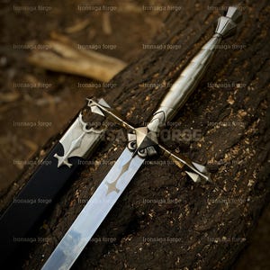 K&ouml;nnte beinhalten: Ein silbernes Schwert mit einem Kreuzdesign auf der Klinge und einem dekorativen Knauf, das auf einem verwitterten Holzstamm liegt. Eine schwarze Scheide mit silbernen Akzenten liegt neben dem Schwert. Draufsicht.