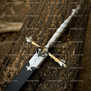 K&ouml;nnte beinhalten: Ein silbernes und schwarzes Schwert mit einem sternf&ouml;rmigen Emblem auf der Scheide liegt auf einer strukturierten Holzoberfl&auml;che. Das Schwert hat einen detaillierten Knauf und Parierstange mit poliertem Finish. Der Text "Ironsaga forge" wiederholt sich im Bild.