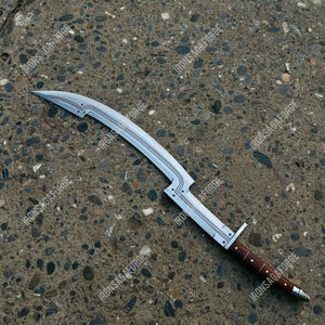 May include: A curved, silver-colored blade with a wooden handle. The blade has a decorative design along the spine and is marked with the text "IRONSAGAFORGE". The handle is dark brown with silver accents.
