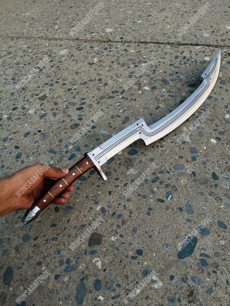 May include: A curved, silver-colored blade with a wooden handle. The blade features decorative star and line patterns. The handle is brown with silver accents. The knife is held by a person's hand.