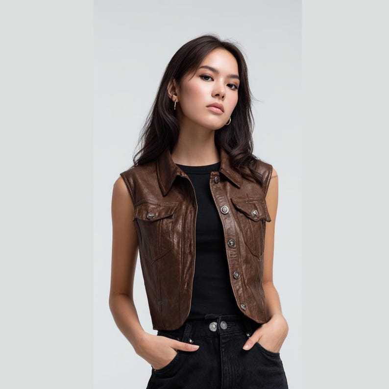 Peut inclure: Un gilet en cuir marron avec un col et deux poches avant. Le gilet a des boutons argent&eacute;s et une coupe ajust&eacute;e. Le mod&egrave;le porte un haut noir et un jean noir.