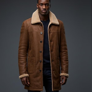 May include: A brown leather coat with a beige shearling collar and trim. The coat has a button-up front, two front pockets, and quilted shoulder details. The model is wearing a navy blue shirt and blue jeans.