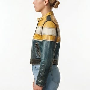 Op de afbeelding: Een kort leren jack met een color-block ontwerp, bestaande uit een mosterdgeel bovendeel, een horizontale witte streep en een donkergroenblauw onderstuk. Het jack is voorzien van een opstaande kraag en lange mouwen.