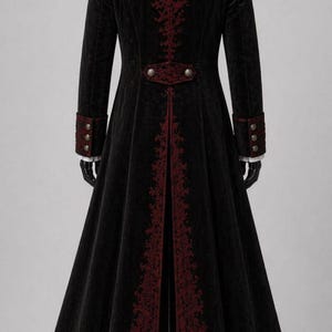May include: A long black coat with red embroidered accents. The coat features a high collar, decorative buttons, and ornate embroidery down the back and along the front edges. The sleeves have red cuffs with three buttons. The coat is displayed on a mannequin.