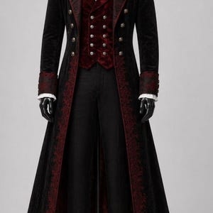 May include: A black velvet coat with red embroidered trim, paired with a red vest and black trousers. The coat features ornate buttons and cuffs, creating a formal, gothic aesthetic. The outfit is displayed on a mannequin.
