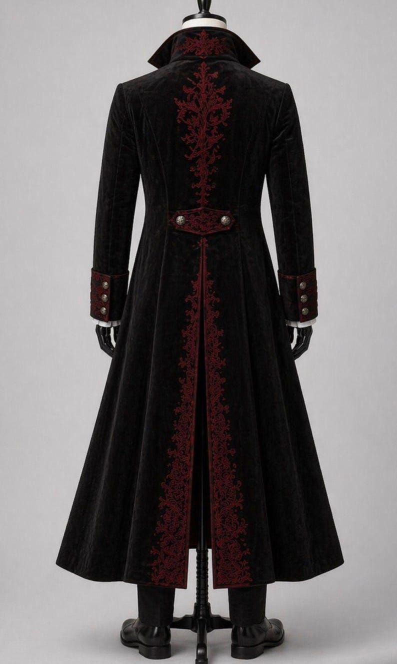 May include: A long black coat with red embroidered accents. The coat features a high collar, decorative buttons, and ornate embroidery down the back and along the front edges. The sleeves have red cuffs with three buttons. The coat is displayed on a mannequin.