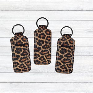 Peut inclure: Trois porte-clés en tissu à imprimé léopard avec des anneaux de clés noirs. Les porte-clés sont en tissu et ont une petite boucle en haut pour attacher les clés.