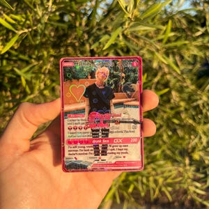 May include: A pink Machine Gun Kelly 2020 trading card. The card features a photo of the artist, with text including "my ex's best friend" and "concert for aliens". The card has a heart graphic and other text.