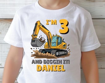 Könnte beinhalten: Ein weißes T-Shirt mit einem gelben Bagger, der im Dreck gräbt. Auf dem Shirt steht "Ich bin 3 und mag es! Daniel"