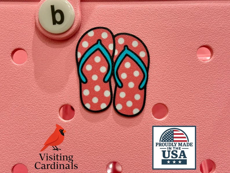 May include: Pink background with a pair of red and white polka dot flip flops with blue straps. The text "Proudly Made in the USA" is below the flip flops.