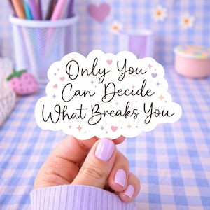 Peut inclure: Un autocollant blanc avec le texte "Only You Can Decide What Breaks You" en écriture noire. L'autocollant a une forme de nuage et est décoré de petits cœurs et d'étoiles. Le fond est un motif à carreaux bleu et blanc.