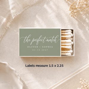 May include: A matchbox with a sage green label that reads "the perfect match" in elegant script, with names and a date below. The box contains white-tipped matches. Labels measure 1.5 x 2.25 inches.