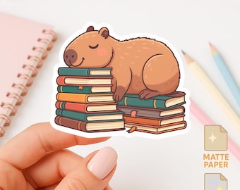 May include: A sticker featuring a cartoon capybara sleeping on a stack of books. The capybara is brown with a light pink blush. The books are various colors, including green, orange, and brown. The sticker options are matte, holographic, and glossy paper.