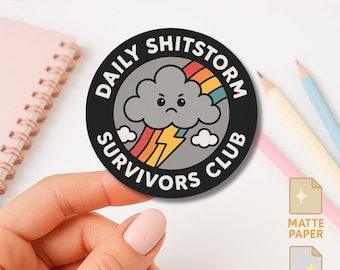 May include: A circular sticker with a black border and white text that reads DAILY SHITSTORM SURVIVORS CLUB. The center features a gray, grumpy storm cloud with a yellow lightning bolt and a colorful rainbow arching behind it.