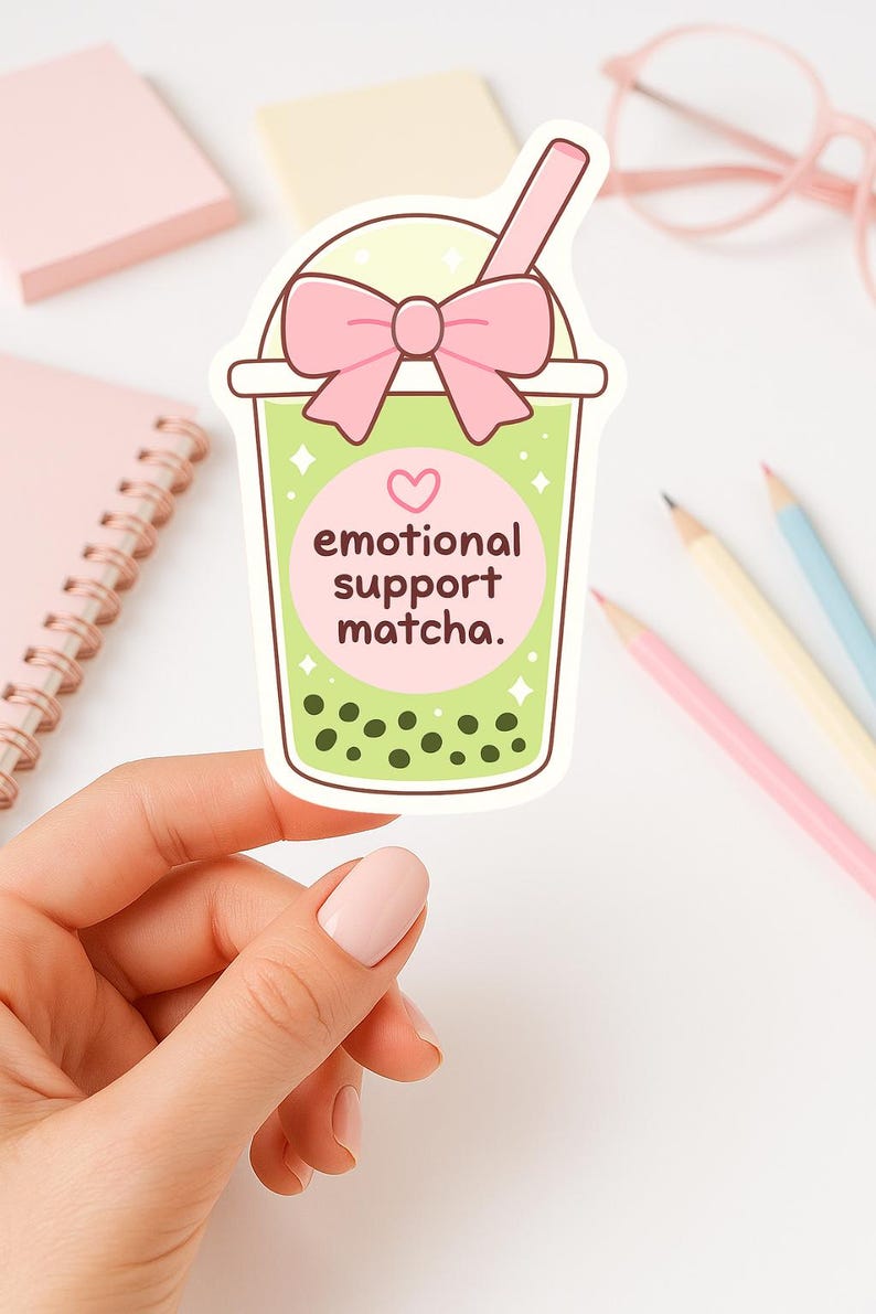 Puede incluir: Una pegatina con una ilustraci&oacute;n de dibujos animados de una bebida de matcha boba. La bebida est&aacute; en un vaso transparente con un lazo rosa, una pajita rosa y las palabras "emotional support matcha". La bebida tiene l&iacute;quido verde y boba verde oscuro.