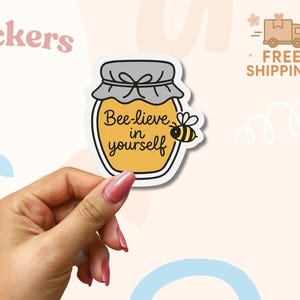 Adesivo "Bee-credi in te stesso" - Adesivo in vinile con un simpatico gioco di parole tra api e un barattolo di miele, affermazione estetica positiva per laptop, bottiglia d'acqua o quaderno