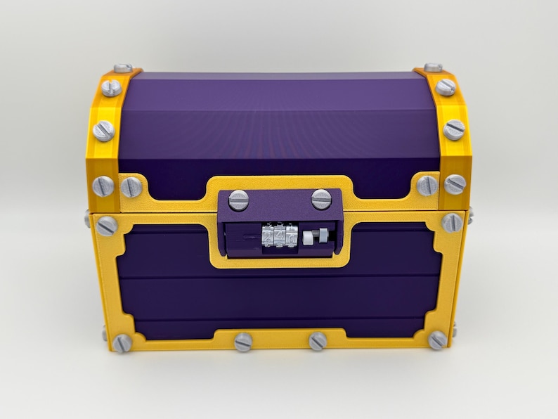 May include: A purple treasure chest with gold trim and silver rivets. The chest has a combination lock on the front. The chest is made of a hard material and has a rectangular shape.