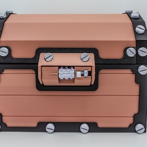 May include: A copper-colored chest with black trim and silver-colored screws. The chest has a combination lock and is designed with a classic, vintage aesthetic. The chest is a decorative storage container.